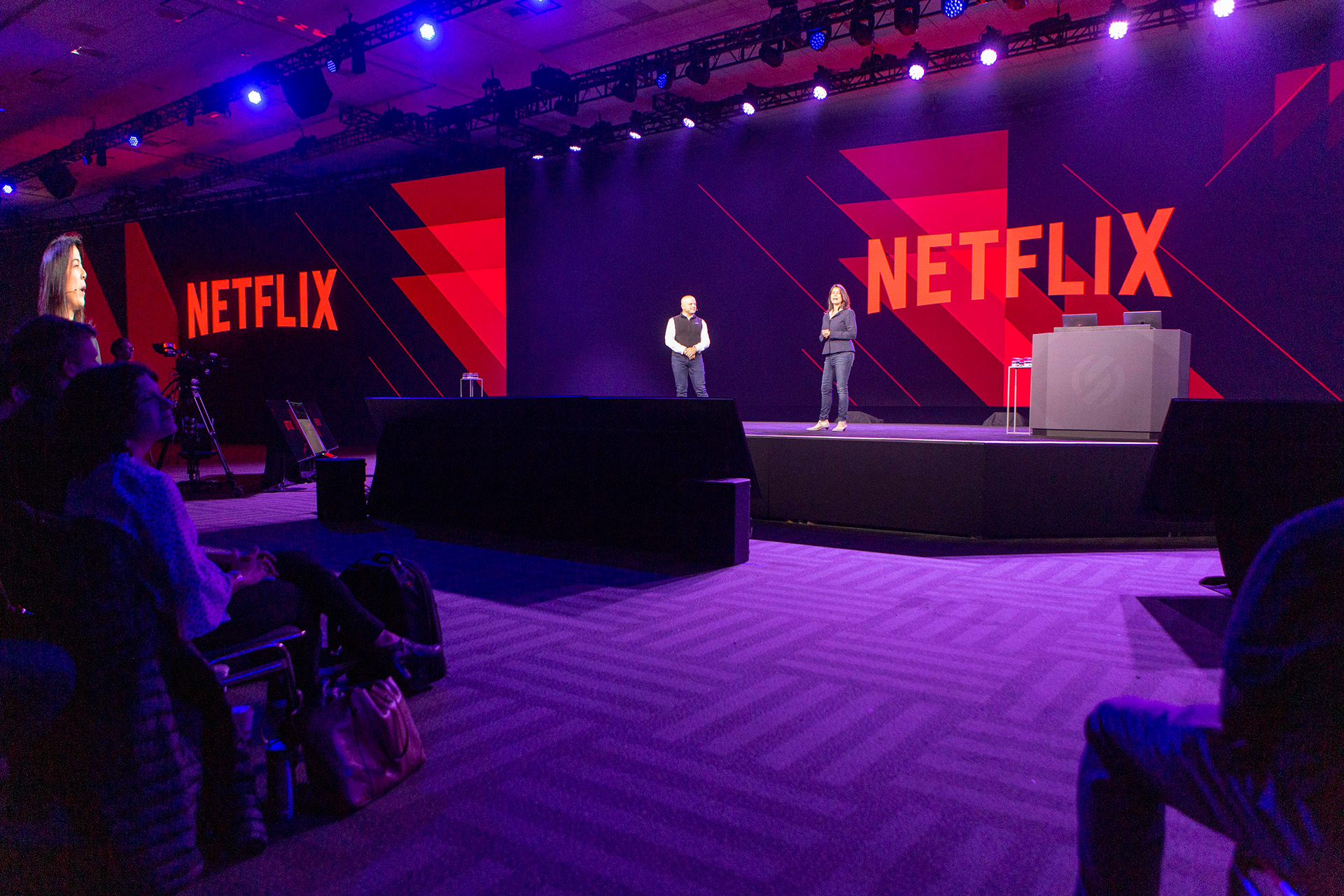 Netflix-branded stage with two speakers under bold red and black set design